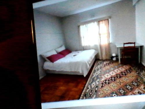 a bedroom with a bed with red pillows and a window at Highbury Square Flat in Cape Town