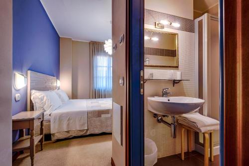 a bathroom with a sink and a bedroom with a bed at La Grotta Hotel in San Marino
