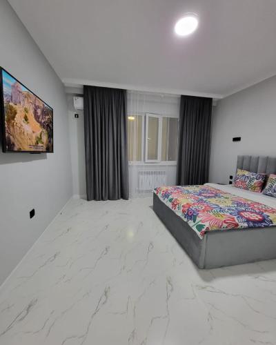 um quarto com uma cama e uma televisão na parede em К7 family em Atyrau