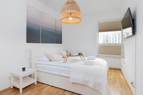 a white bedroom with a bed and a tv at Stadion Apartment with Parking by Renters in Gdańsk