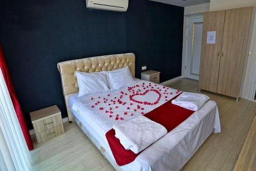 a bed with a red and white blanket with a heart on it at Airport Güllük Otel in Milas