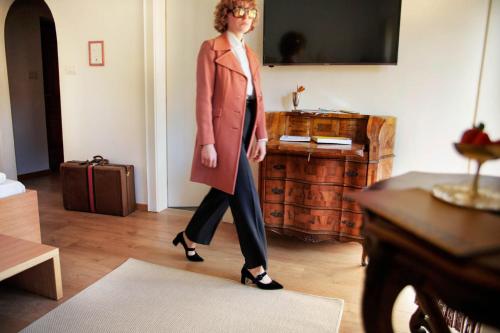 a woman walking in a room wearing a trench coat at Weisses Rössl in Caldaro