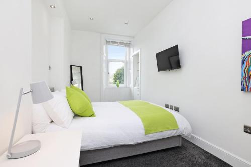 a white bedroom with a bed and a tv at One bed apartment in the heart of Innerleithen in Innerleithen