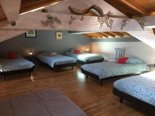 4 łóżka w pokoju z drewnianą podłogą w obiekcie Ferme de Simondon w mieście Plats