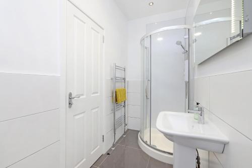 Baño blanco con lavabo y espejo en One bed apartment in the heart of Innerleithen, en Innerleithen