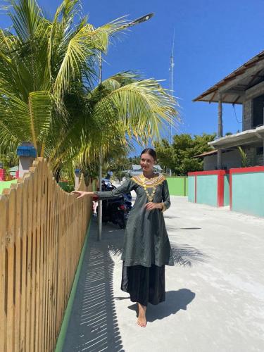 a woman in a dress standing next to a fence at Dhonveli Inn, Bandidhoo in Meedhoo