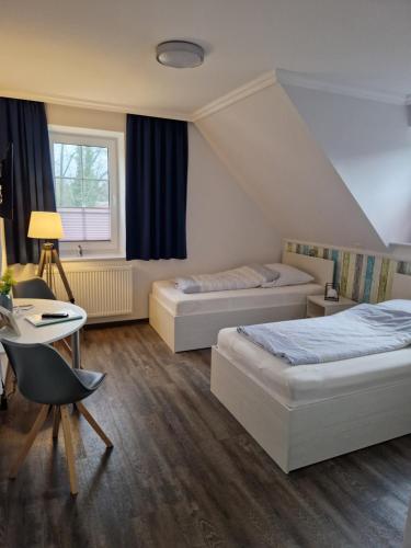 a bedroom with two beds and a table and a desk at Gästequartier Schlummerkasten in Sievern