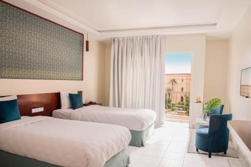 um quarto de hotel com duas camas e uma janela em Hotel Safia em Marrakech