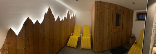 Habitación con sillas amarillas y pared de madera. en Pension Posthansl, en Heiterwang