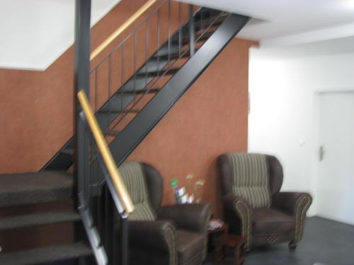 two chairs in a living room with a staircase at Gästequartier Schlummerkasten in Sievern