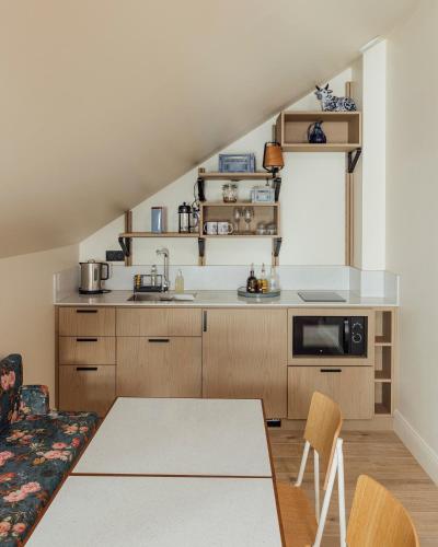 a kitchen with wooden cabinets and a table and chairs at Hôtel Préfecture - Entrée autonome, réception en ligne - Encore Mieux in Limoges