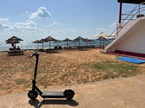 a scooter parked on a beach with tables and umbrellas at Vrissiana Boutique Beach Hotel in Protaras