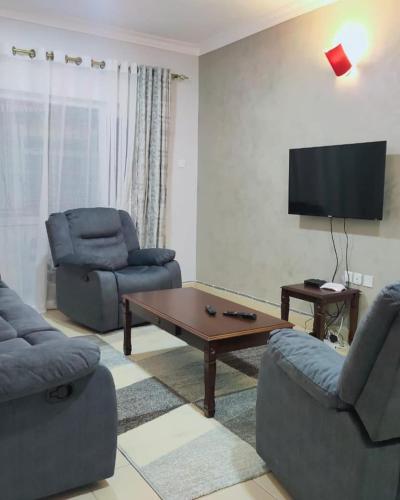 - un salon avec deux chaises et une télévision dans l'établissement COSY MTWAPA THREE BEDROOM APARTMENT, à Mombasa