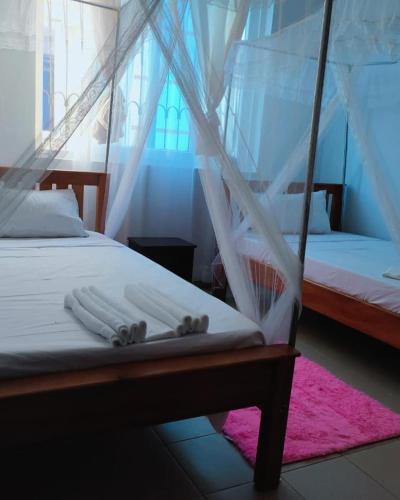 - une chambre avec 2 lits et des moustiquaires dans l'établissement COSY MTWAPA THREE BEDROOM APARTMENT, à Mombasa