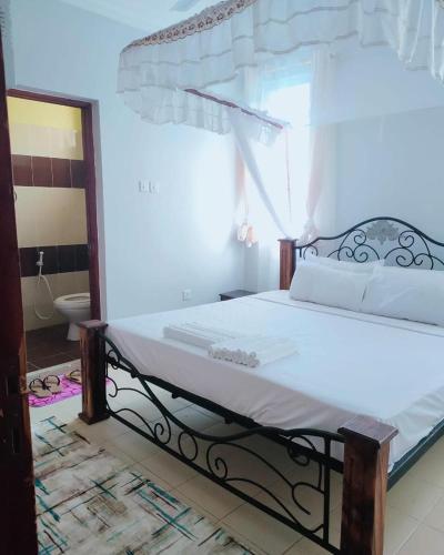 - une chambre avec un lit et une salle de bains avec un miroir dans l'établissement COSY MTWAPA THREE BEDROOM APARTMENT, à Mombasa