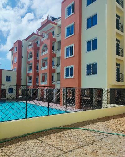 une clôture en face d'un bâtiment avec piscine dans l'établissement COSY MTWAPA THREE BEDROOM APARTMENT, à Mombasa