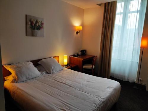 a hotel room with a bed with a desk and a window at Hôtel La Rivière in Entraygues-sur-Truyère