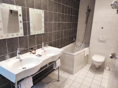 a bathroom with a sink and a tub and a toilet at Hôtel La Rivière in Entraygues-sur-Truyère