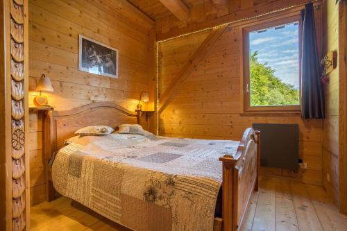 una camera con un letto in una baita di tronchi di Les Esseroliettes ad Arith