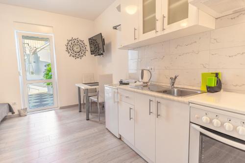a kitchen with white cabinets and a sink and a table at Apartments Didan in Cavtat