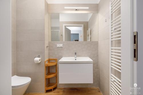 ein Badezimmer mit einem weißen Waschbecken und einer Toilette in der Unterkunft KOŁOBrzegu Apartamenty by Jantar Apartamenty Kołobrzeg in Kołobrzeg