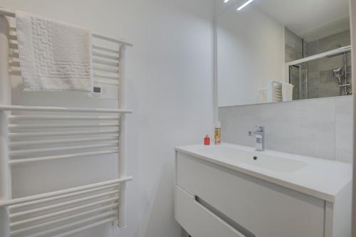 a white bathroom with a sink and a mirror at Les forges 2 pièces RDC in Avoine