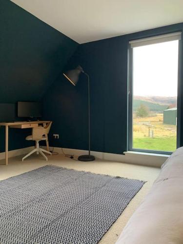 a bedroom with a blue wall with a desk and a window at Highland Hideaway in secluded riverside location in Garve