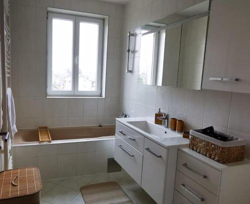 y baño con lavabo, bañera y espejo. en Vienna's Nature Corner - charming rooftop family apartment, en Gerasdorf bei Wien