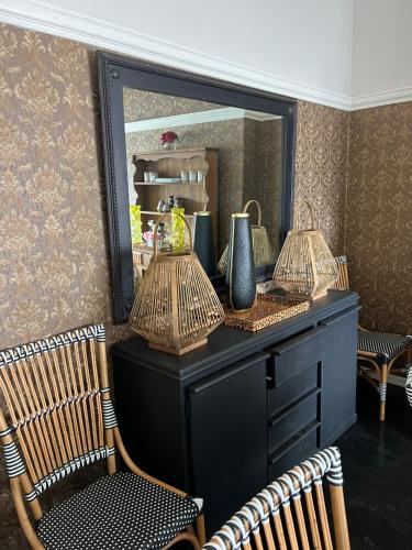 a black dresser with two chairs and a mirror at Smithgrove Guesthouse in Pietermaritzburg