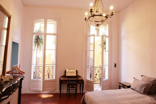 a bedroom with a bed and a table and windows at chambre d'hôtes hyper central in Perpignan