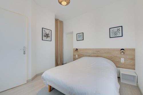 a bedroom with a white bed and two pictures on the wall at Les forges 2 pièces étage in Avoine