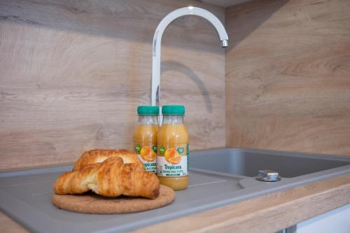 a sink with two bottles of orange juice and a croissant at Les forges 2 pièces étage in Avoine