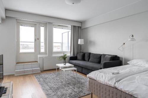a white bedroom with a bed and a couch at 2ndhomes Tampere "Koskenranta" Apartment - Sauna, Rooftop Terrace, Amazing Views & Free Parking in Tampere