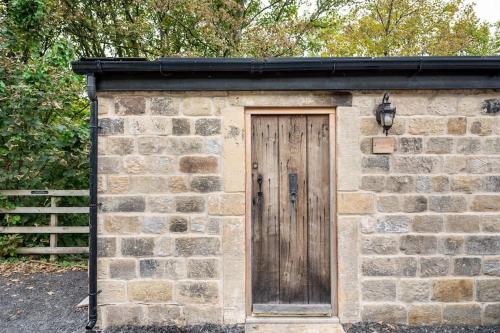 a small brick building with a wooden door at The Keep at Castlegate - Luxury detached retreat in Cragg vale, Hebden Bridge in Mytholmroyd