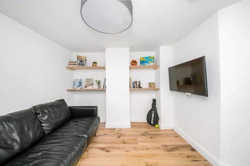 a living room with a black leather couch and a flat screen tv at The Keep at Castlegate - Luxury detached retreat in Cragg vale, Hebden Bridge in Mytholmroyd