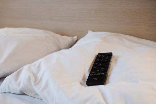 a remote control sitting on top of a bed at La Petite Maison appartement 1 in Avoine
