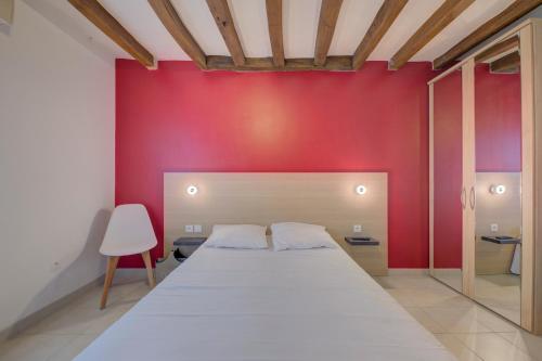 a bedroom with a white bed and a red wall at La Petite Maison appartement 1 in Avoine