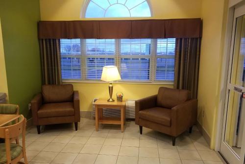 a living room with two chairs and a lamp and a window at Microtel Inn & Suites by Wyndham Delphos in Delphos
