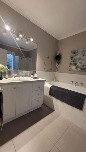 a bathroom with two sinks and a tub and a mirror at Quiet family retreat getaway - Wildlife Park, Sovereign Hill, Kryall Castle and city at your door - modern apartment, 8 guests in Ballarat