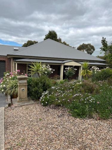a house with a bunch of flowers in front of it at Quiet family retreat getaway - Wildlife Park, Sovereign Hill, Kryall Castle and city at your door - modern house, 8 guests, 4 bedrooms, 5 beds in Ballarat