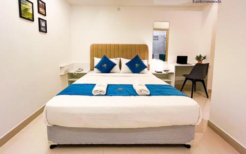 um quarto com uma cama grande e almofadas azuis em Easternwoods Hotels em Bangalore