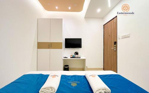 una camera con letto con lenzuola blu e TV di Easternwoods Hotels a Bangalore