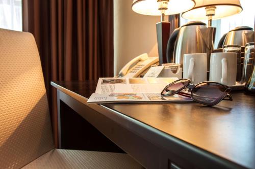 a desk with a pair of glasses and a newspaper at Best Western Lozenetz Hotel in Sofia