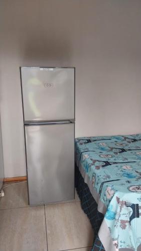 a refrigerator in the corner of a room with a bed at Jay's Guest House in Witbank