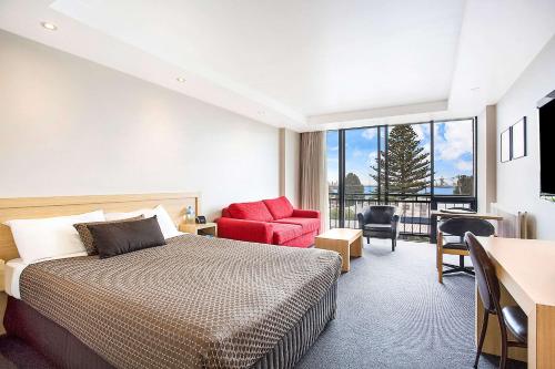 a hotel room with a bed and a red chair at Richmond Henty Hotel in Portland