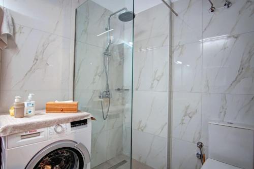 uma casa de banho com um chuveiro e uma máquina de lavar roupa em Kellys Apartment em Anemómylos