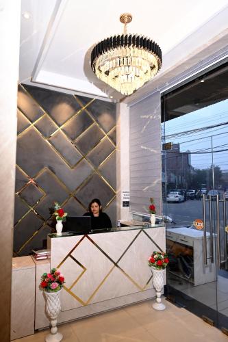 a woman sitting at a reception desk in a building at Hotel Diamond Villa l Hotel Near Golden Temple Amritsar l Hotel In Amritsar l Best Hotel In Amritsar in Amritsar