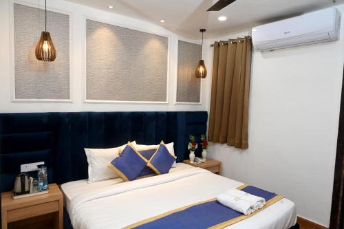 a bedroom with a bed with a blue headboard and windows at Hotel Diamond Villa l Hotel Near Golden Temple Amritsar l Hotel In Amritsar l Best Hotel In Amritsar in Amritsar