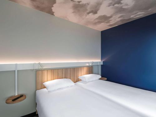 um quarto com uma cama grande e uma parede azul em ibis Lyon Est Meyzieu em Meyzieu