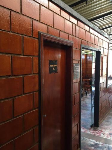 a brick wall with a door with a sign on it at Hotel Buriti Itupeva in Itupeva